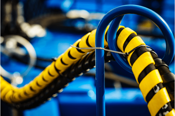 Hydraulic connections hoses in black and yellow spiral guard wraps. Machinery industrial detail